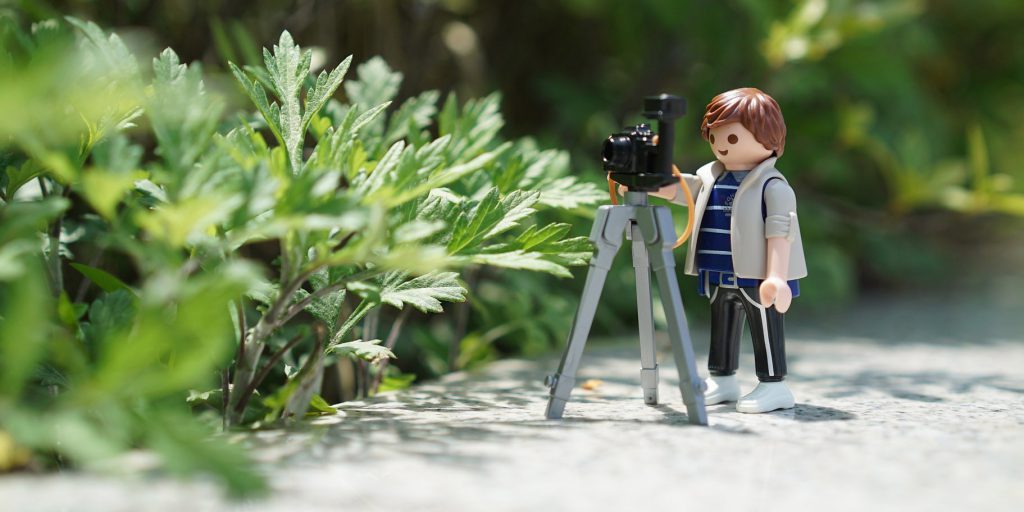 duplo lego photographer with camera in front of plants