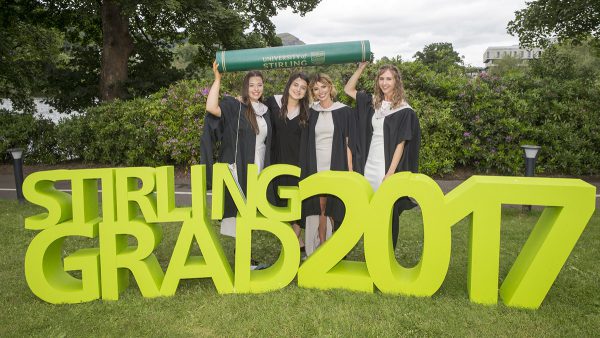 Stirling graduates holding Graduation props next to Airthrey Loch at summer Graduation 2017