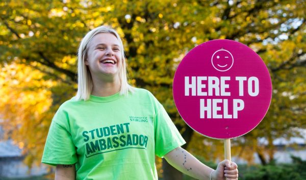 Student ambassador at Open Day with a 'here to help' sign