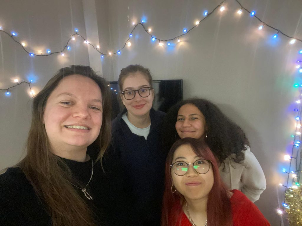A group of students in student accommodation. Fairy lights can be seen in the background.