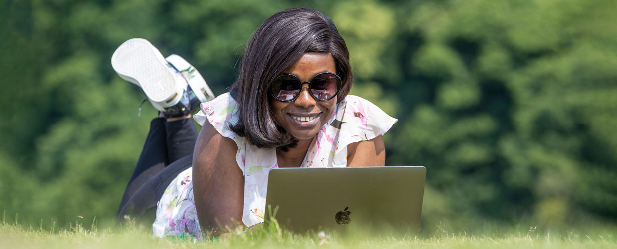 A student working on her laptop on a sunny day