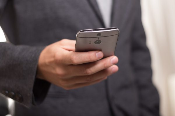 Someone in a suit using their mobile phone.