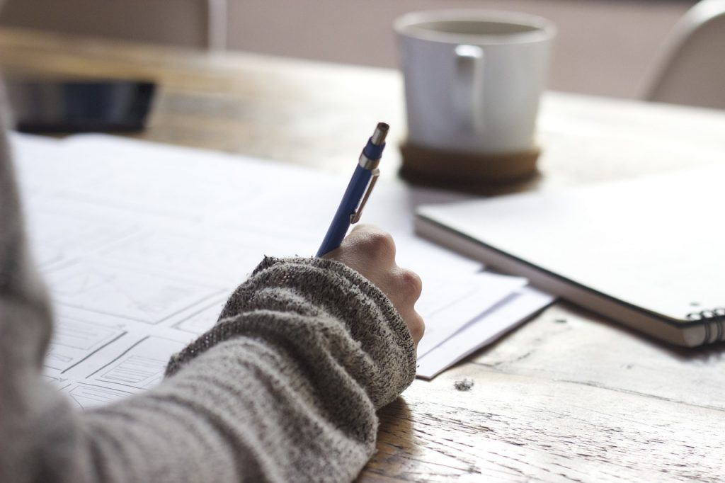 Student with pen in hand writing at desk