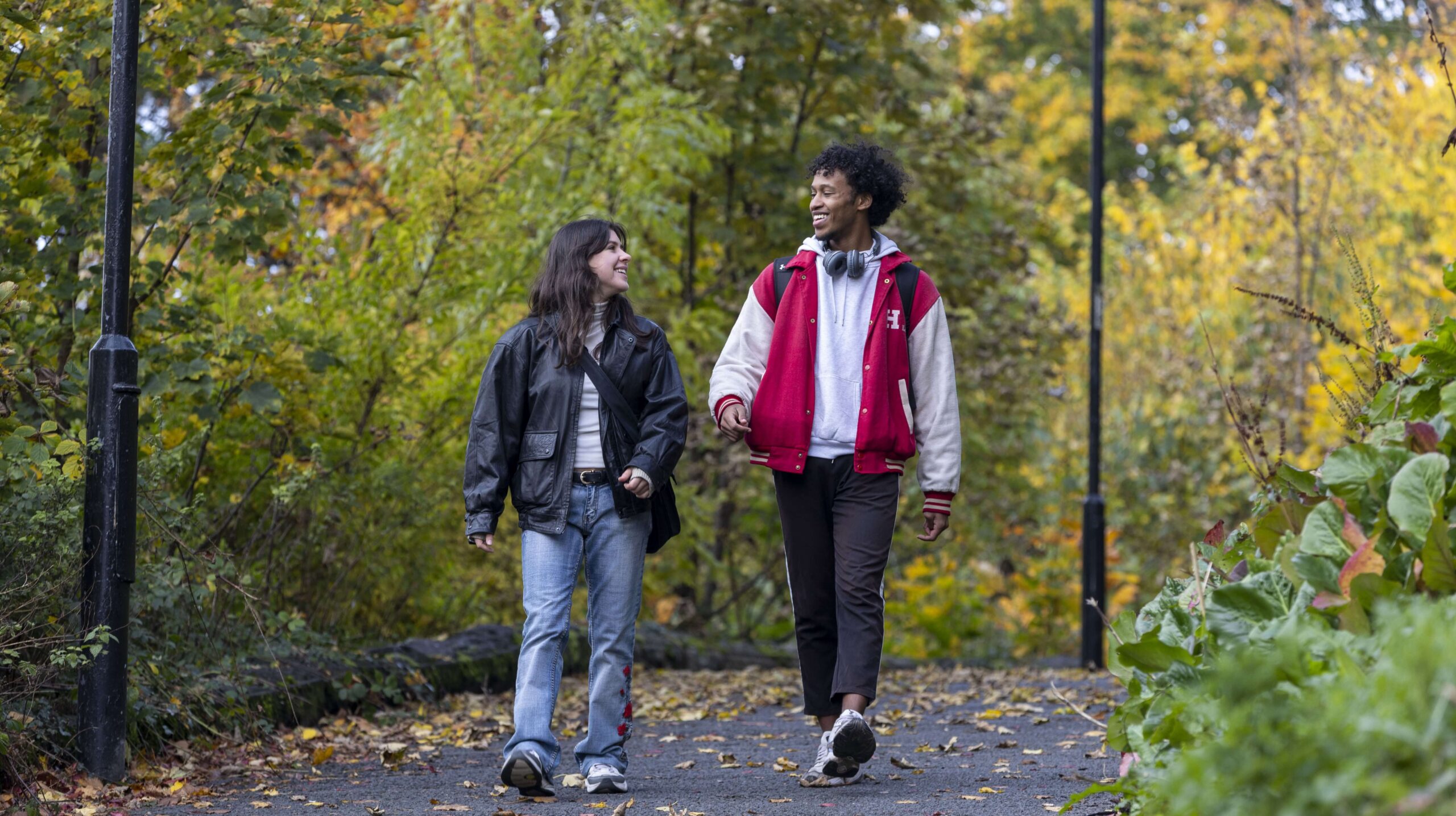 Two students walking around campus in autumn