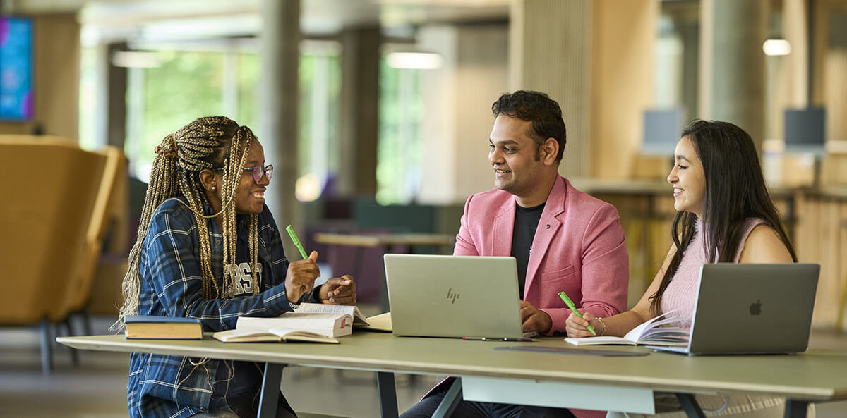 Three students studying together in campus central