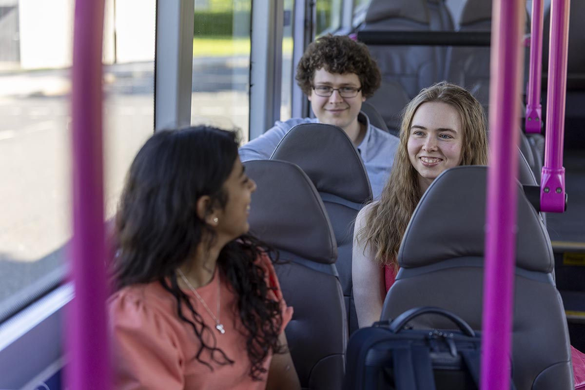 Picture of three students sitting on a bus together