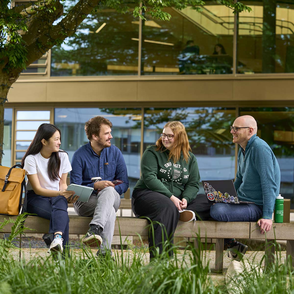 Four students sitting on a bench in Queen's Court