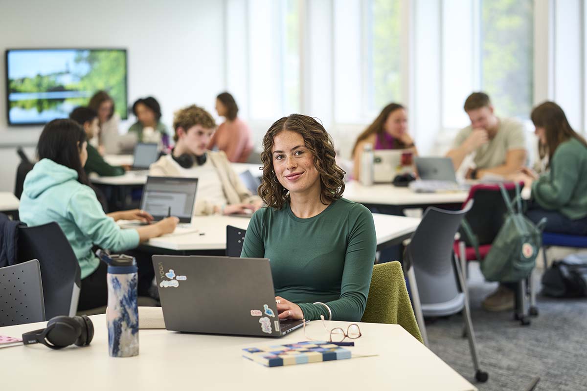 Female student sitting in classroom with laptop