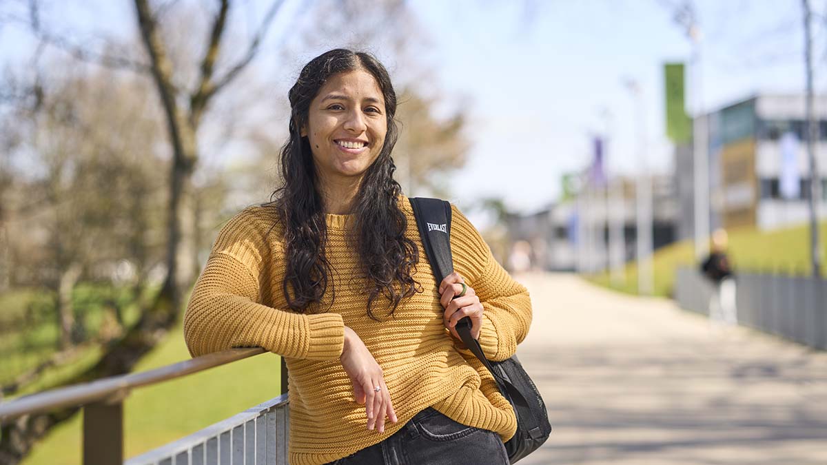 Student with backpack leaning against a rail on campus